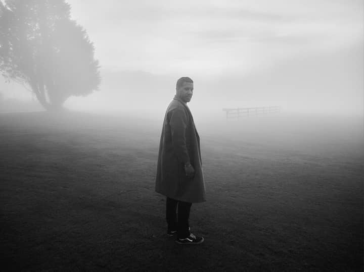 Black and white photo of a man in a foggy landscape, adding mystery and intrigue.