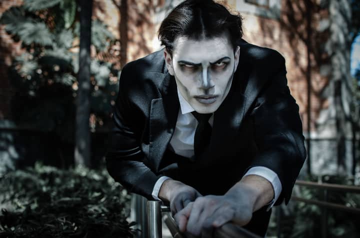 A man in a gothic Tim Burton-inspired costume poses dramatically outdoors, ideal for Halloween themes.