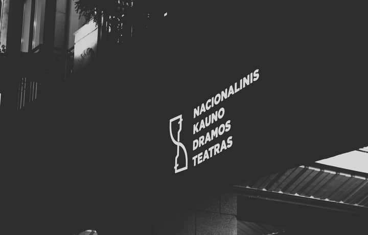 Illuminated signage of Kaunas Drama Theatre in black and white low angle shot.