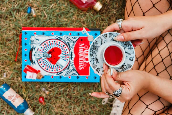 Tea party scene with Alice in Wonderland book and vibrant visuals, outdoors.