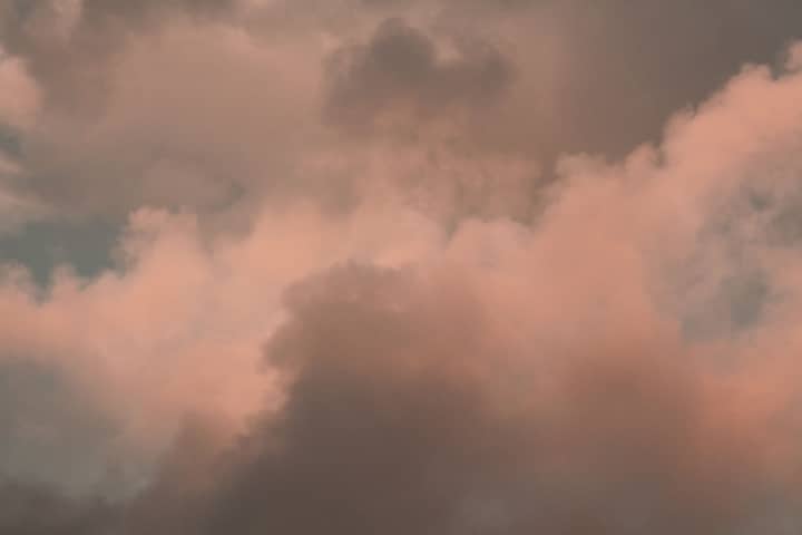 A serene and dramatic cloudscape featuring soft hues of pink and gray, capturing a tranquil sky moment.
