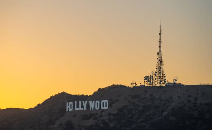 The iconic Hollywood sign captured at sunset, Los Angeles skyline in silhouette.