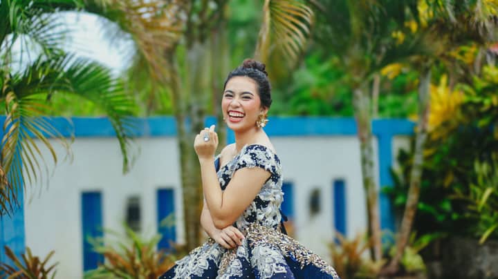 Happy woman in a luxurious dress laughing in a lush tropical setting.