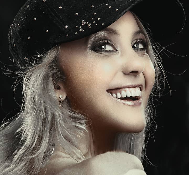 Charming portrait of a woman wearing a decorated hat, showcasing elegance and joy.