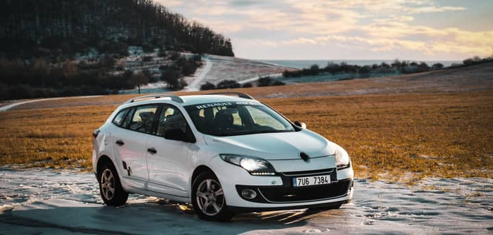 White Renault car parked on a snowy field in Czechia, capturing a serene winter landscape.