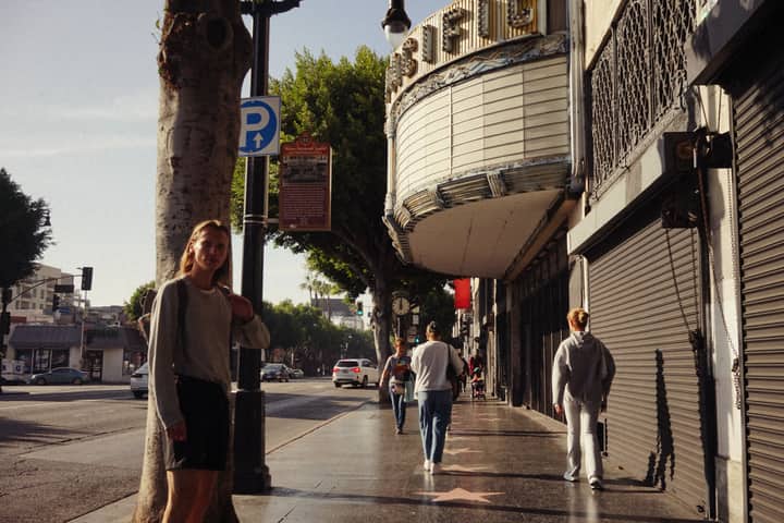 People strolling by a classic theater in an urban street setting, capturing local culture.