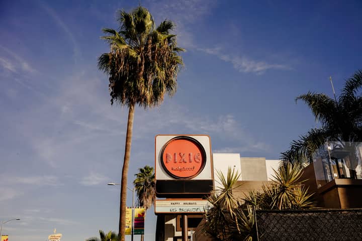Sunny day showcasing iconic Dixie Hollywood signage with palm trees and clear blue sky.