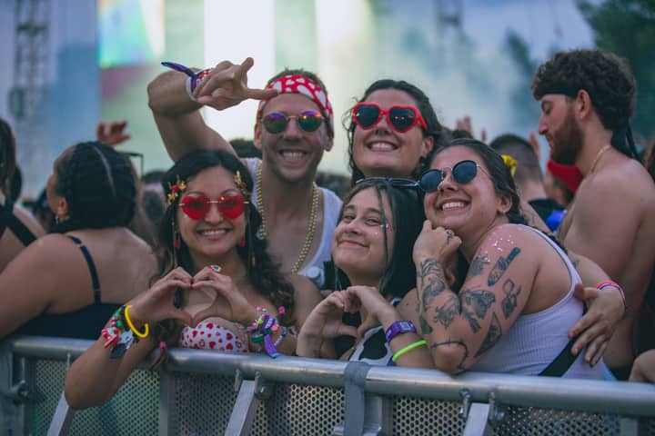 Joyful group of friends enjoying an outdoor music festival with colorful accessories and tattoos.
