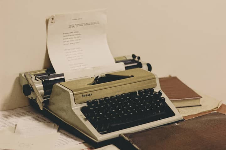 A classic typewriter with paper, surrounded by books, evokes retro vibes.
