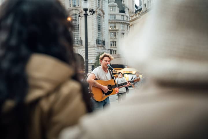 A street musician plays guitar in bustling Piccadilly Circus, London.
