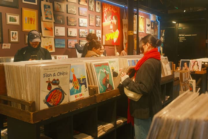 A bustling scene of customers browsing vinyl records in a cozy London store.