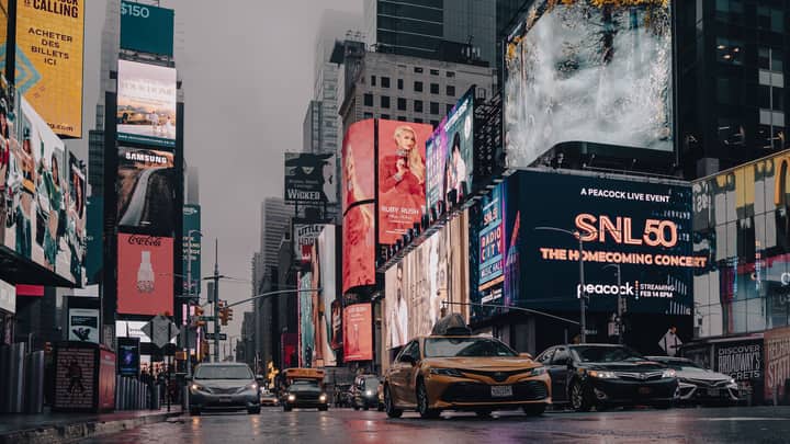Glistening Times Square with neon lights and traffic during a moody evening after rain.