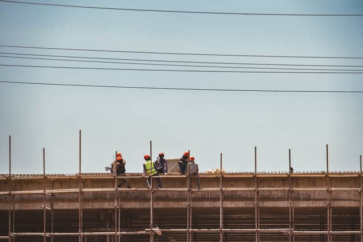 Construction workers on scaffold against a clear sky in Nairobi, Kenya.