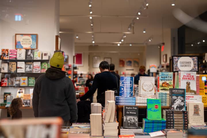 Warmly lit bookstore in New York City with people browsing through bookshelves.