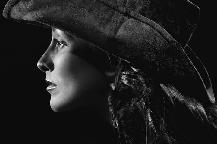 Elegant black and white side profile portrait of a woman wearing a hat.