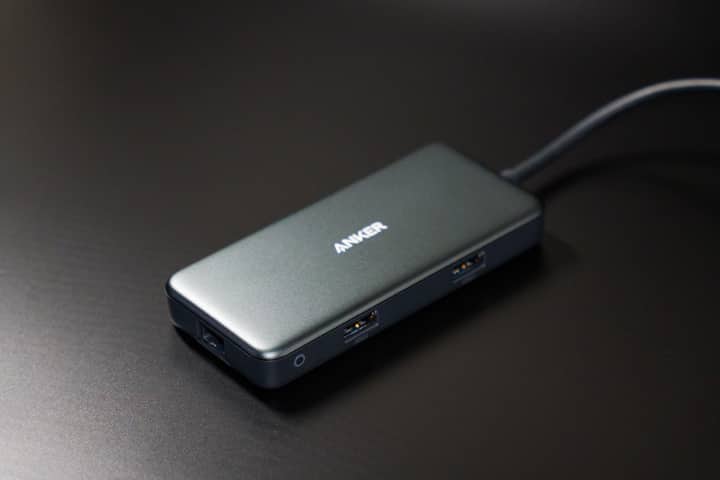 Compact USB-C hub on dark desk surface with visible USB ports.