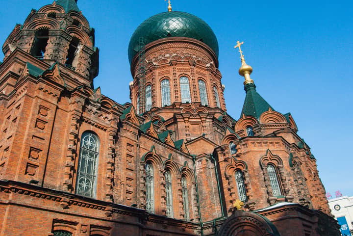 Photo of the iconic St. Sophia Cathedral featuring red brick architecture under a blue sky.