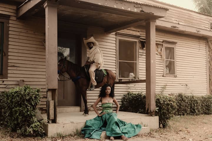 Man on horseback and woman in traditional dress outside a rustic building in Nigeria.