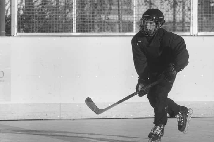 Black and white photo of a person playing roller hockey outdoors.