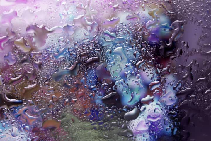 Vibrant abstract texture of raindrops on a window with a purple and blue background.