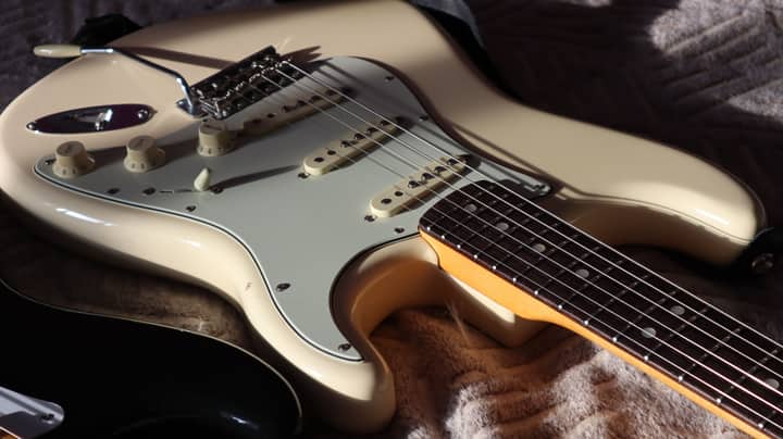 Detailed close-up of a cream Stratocaster electric guitar highlighting strings and body.