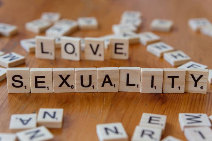 Wooden letter tiles spelling 'Love' and 'Sexuality' on a wooden table.