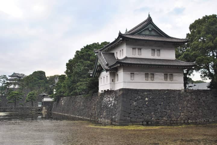Serene exterior of Tokyo's Imperial Palace surrounded by lush greenery and stone walls.