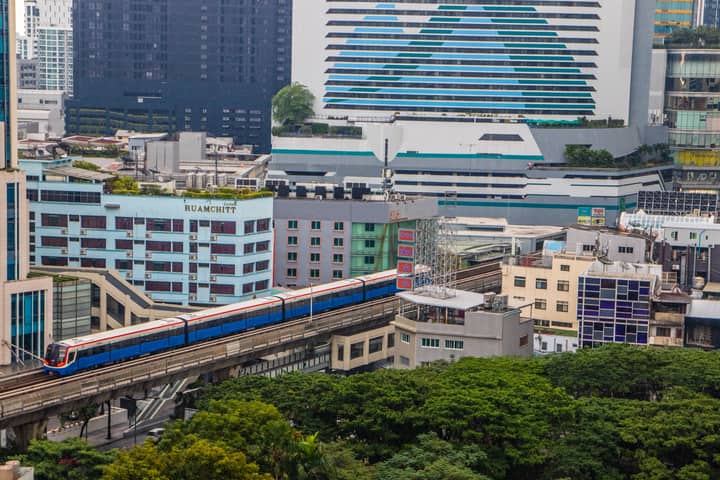 View of Bangkok cityscape featuring the BTS Skytrain amidst modern buildings.