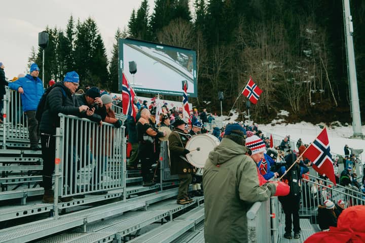 A lively crowd with flags at a winter sports event in Norway, showcasing national pride.