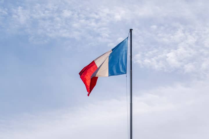 The French national flag waving against a blue sky in Paris, France.