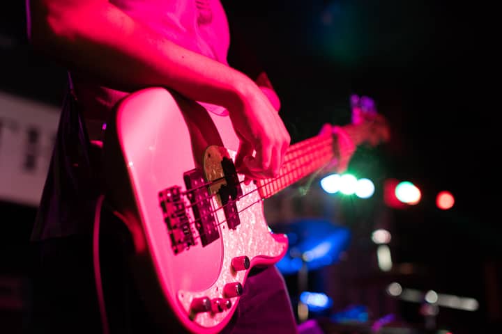 Close-up of a musician playing bass guitar on a vibrant Atlanta stage during a live gig.