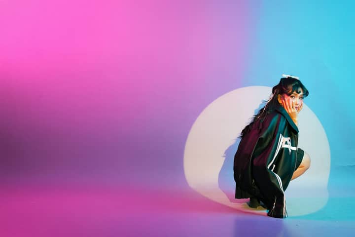Vibrant studio portrait featuring a young woman surrounded by colorful lighting effects.