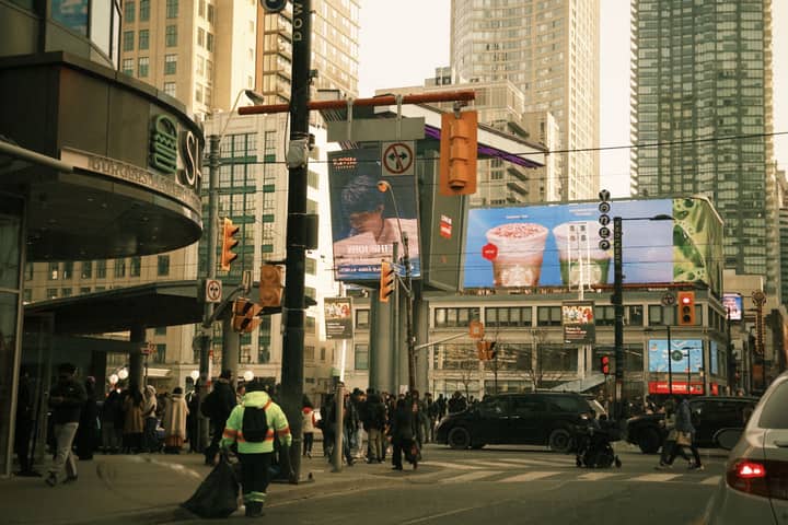 Bustling city scene in downtown Toronto with crowds, traffic, and towering skyscrapers.
