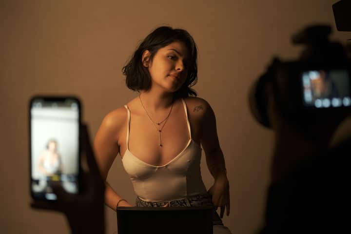 Artistic portrait of a young woman in a studio with camera and phone.