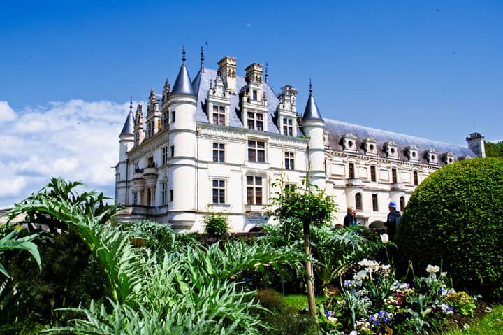 Majestic Château de Chenonceau in France with blooming gardens during a sunny spring day.
