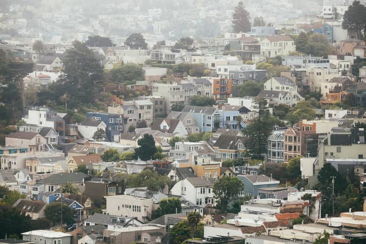 Scenic view of the foggy San Francisco hills with colorful houses under a cloudy sky.
