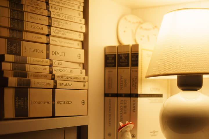 Warmly lit bookshelf with classic novels and a glowing table lamp.