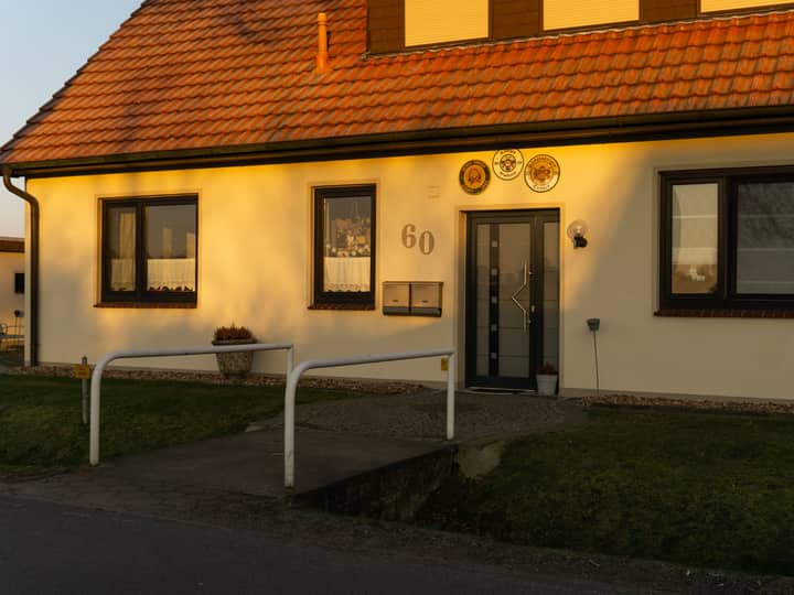 Sunlit entrance of a charming house in Achim, Germany, casting warm shadows at dusk.