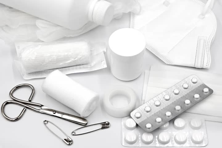 A flat lay of essential first aid supplies and medical equipment on a white background.