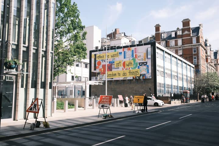 City street scene with a colorful billboard and road closure signs.