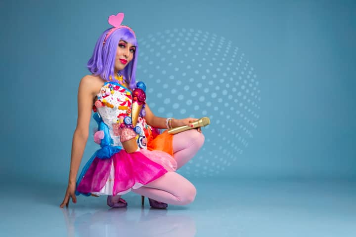 Vibrant cosplay featuring a candy-themed costume with a purple wig and playful accessories.