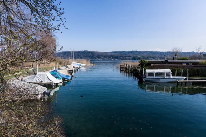 Peaceful Swiss lake scene with docked boats and clear blue sky in springtime