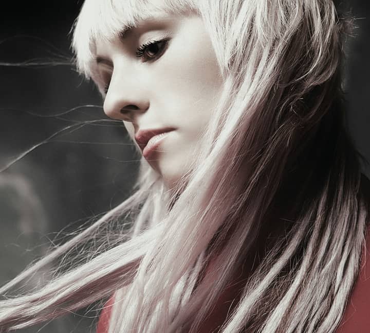 Artistic portrait of a woman with flowing platinum hair and soft lighting.