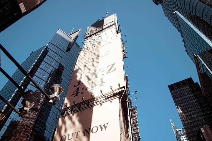 Low angle view of skyscrapers and advertisement in New York City, showcasing urban architecture.