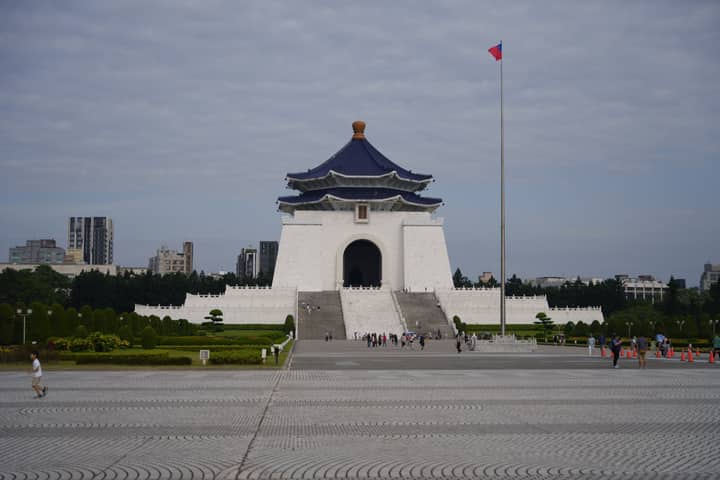 Chiang Kai-shek Memorial Hall with Taiwanese flag in Taipei. Iconic landmark with visitors.