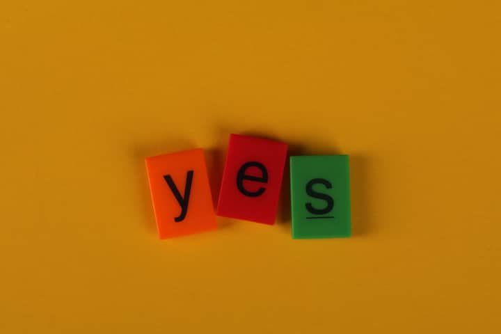 Brightly colored tiles spell 'yes' on a vibrant yellow background.