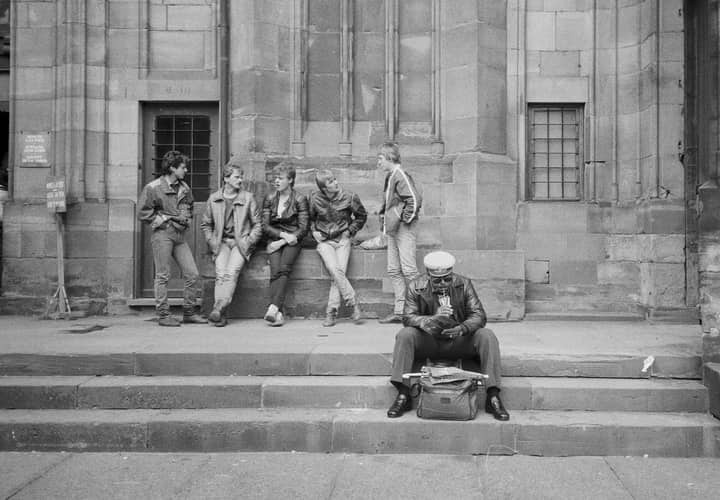 Group of men in front of historic Reims building, France. Casual 1980s setting.