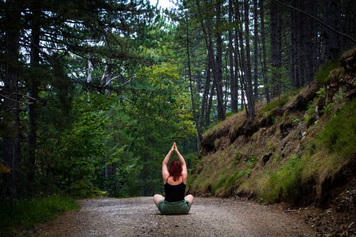 Woman practicing yoga in a tranquil forest setting, symbolizing peace and nature.