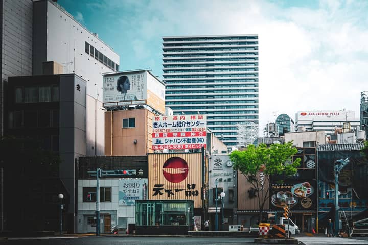 Vibrant city view with modern architecture and advertisement signs, showcasing urban life.