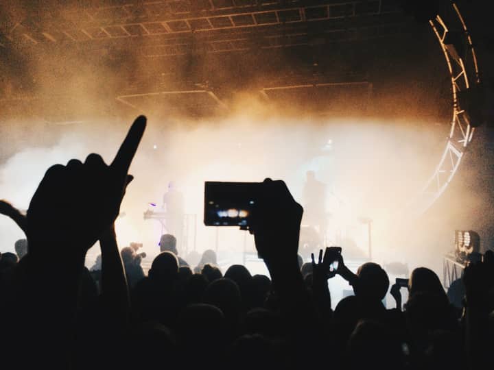 A vibrant concert scene with silhouettes of an energetic crowd capturing the moment on mobile phones.